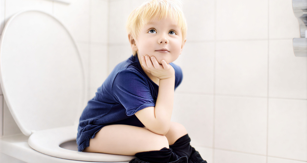Young child with constipation symptoms sitting on toilet during bowel movement difficulty