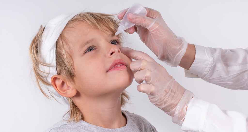 Doctor applying eye drops to child for allergic conjunctivitis treatment