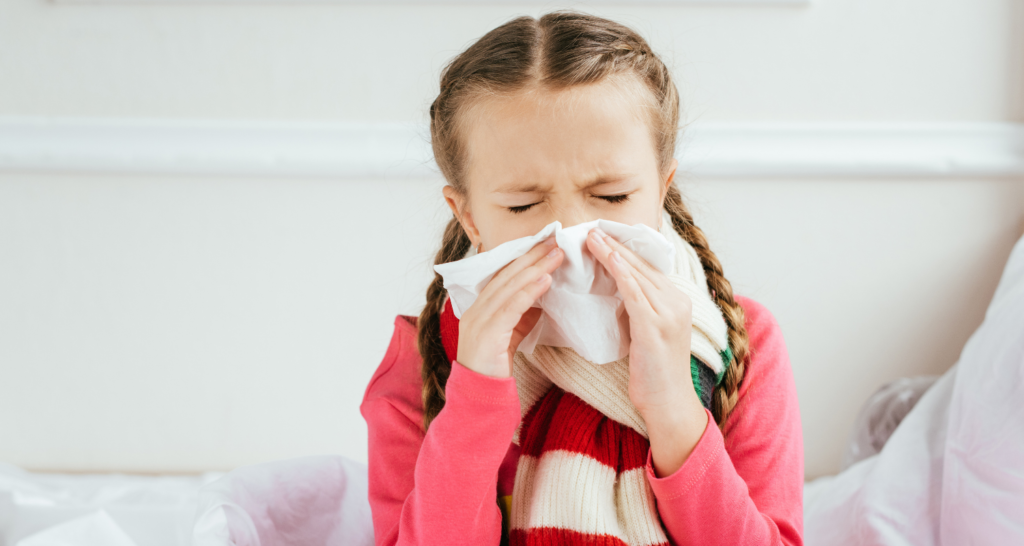 Young girl blowing nose with tissue due to allergic rhinitis and seasonal allergies
