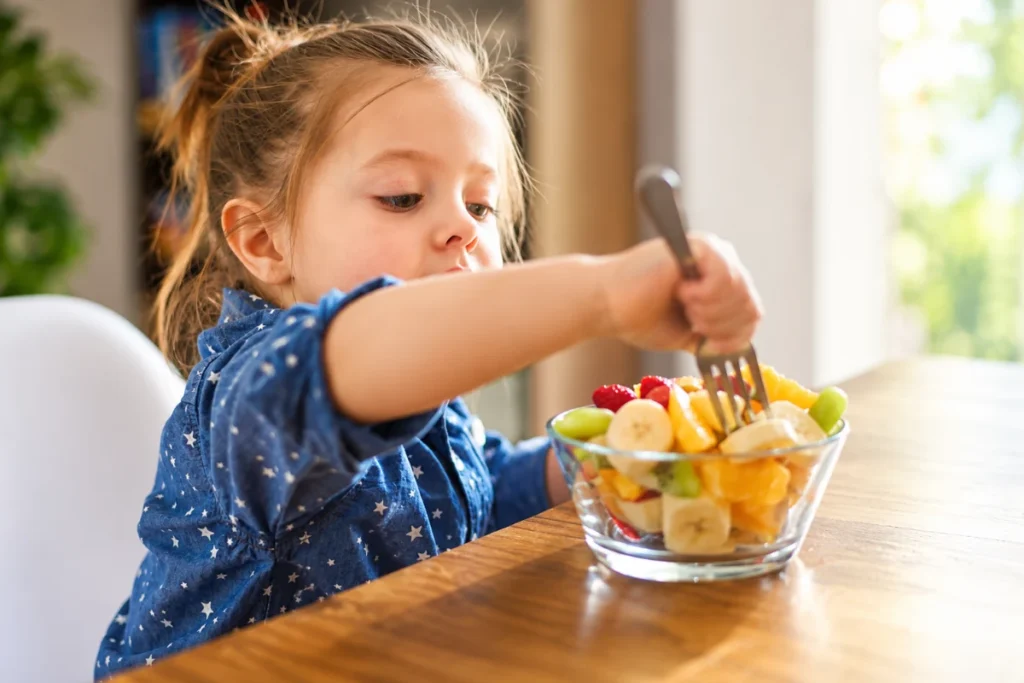 After food allergy immunotherapy Young child eating a bowl of fresh fruit salad at the table