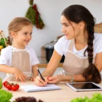 Mother helping her young child with food choices while preparing food in the kitchen