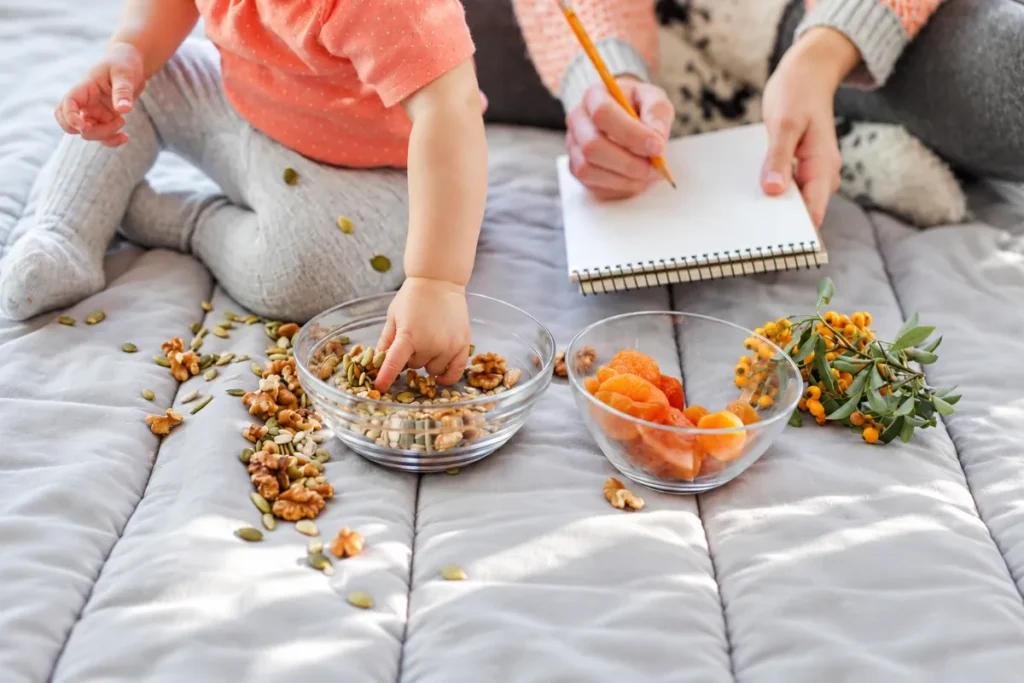 Parent recording food information while a child handles nuts and seeds